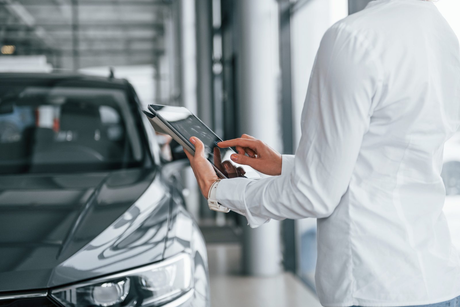 using tablet. woman is in autosalon at daytime